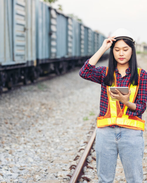 Engenheira asiática nos trilhos da ferrovia segurando um tablet